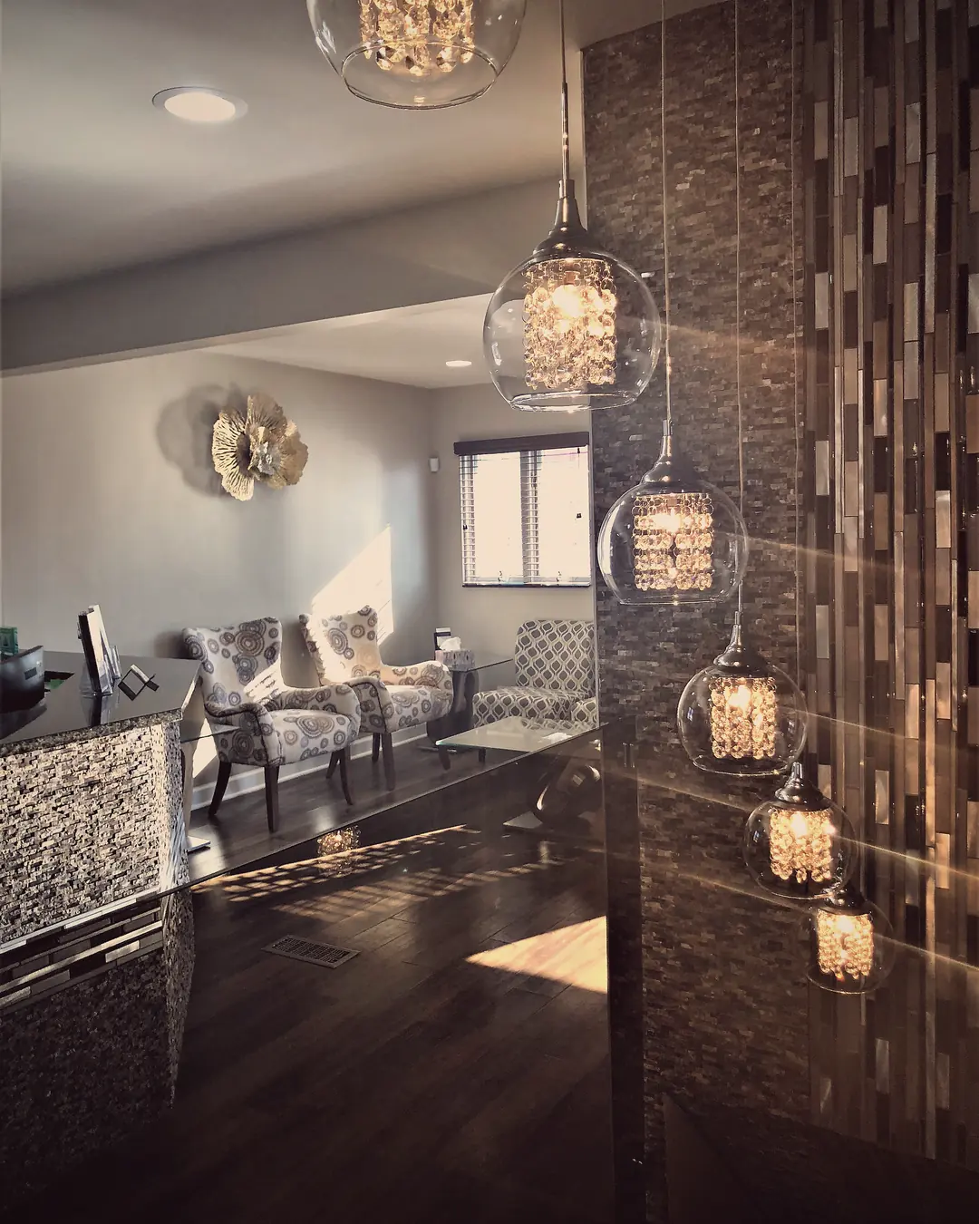 Crystal pendant lights beside a stone mosaic column in the waiting area