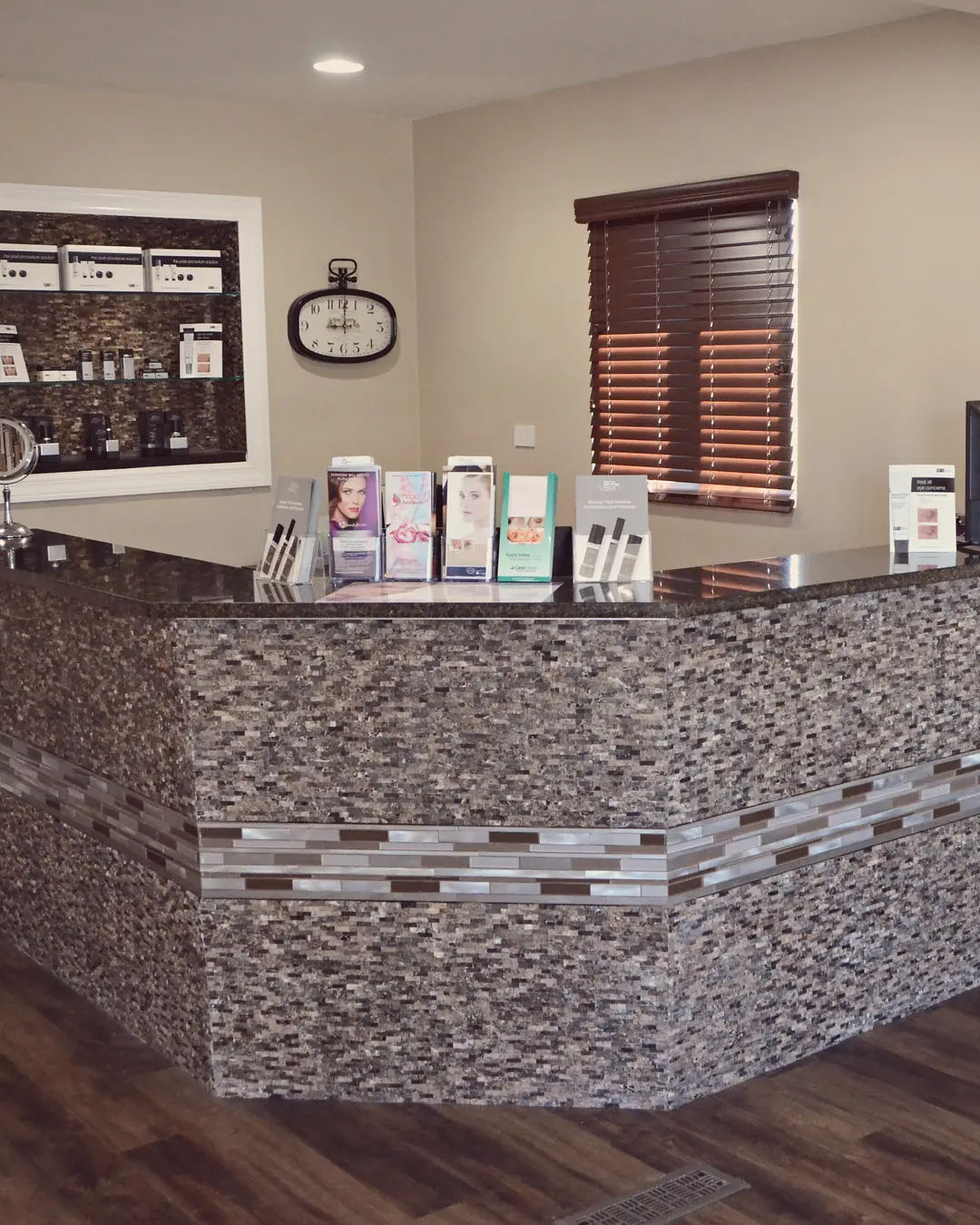 The front desk, a stone mosaic counter with a lit shelf and a clock on the wall